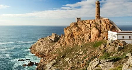 Cape Finisterre lighthouse on a cliff by the sea._140